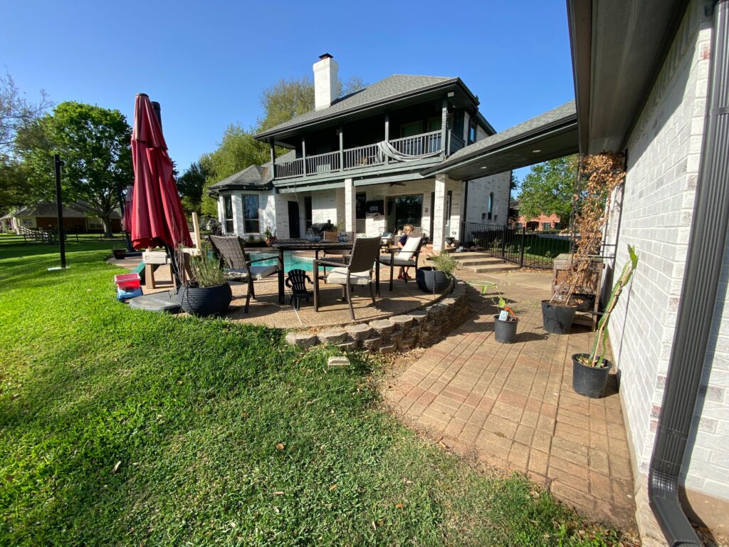 A beautifully designed outdoor living space featuring a covered patio, outdoor kitchen, gas fireplace, and sport court, perfect for entertaining in Houston.