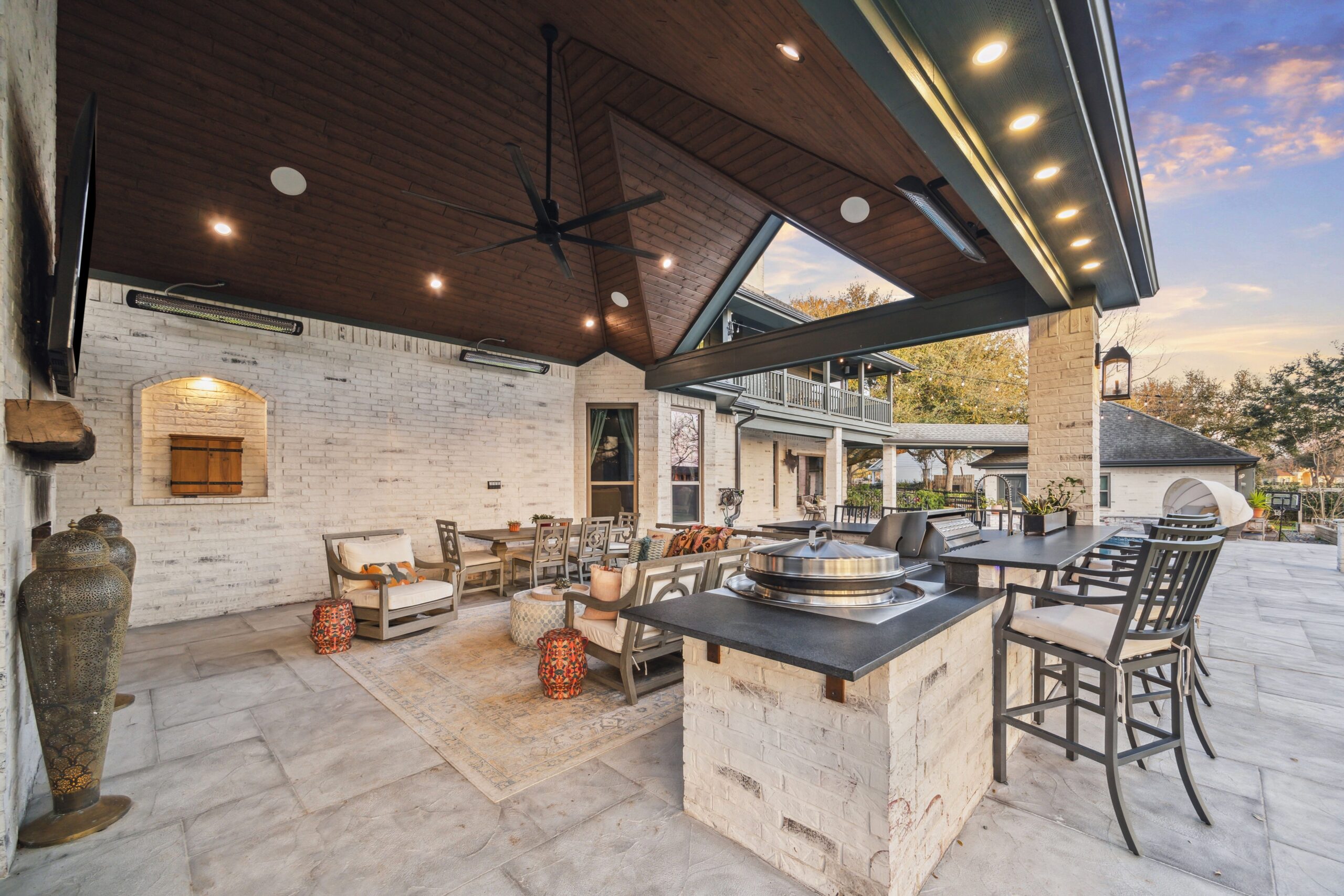 A beautifully designed outdoor living space featuring a covered patio, outdoor kitchen, gas fireplace, and sport court, perfect for entertaining in Houston.